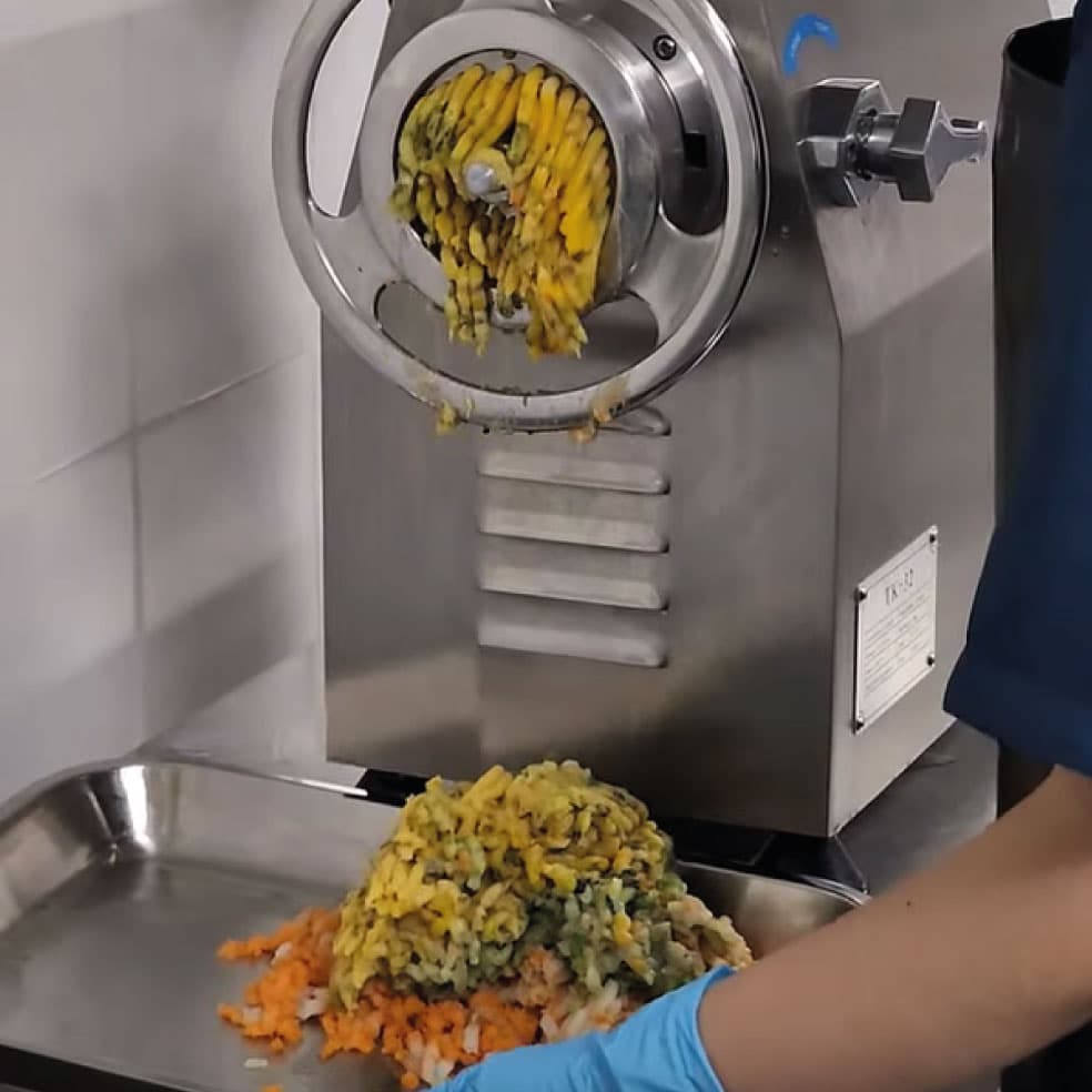 Molino artesanal procesando verduras frescas para la receta Kanuto